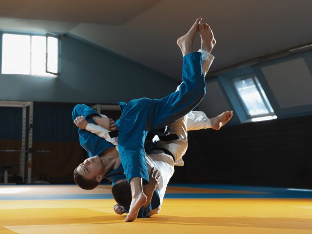 Two young fighters in kimono training martial arts in the gym